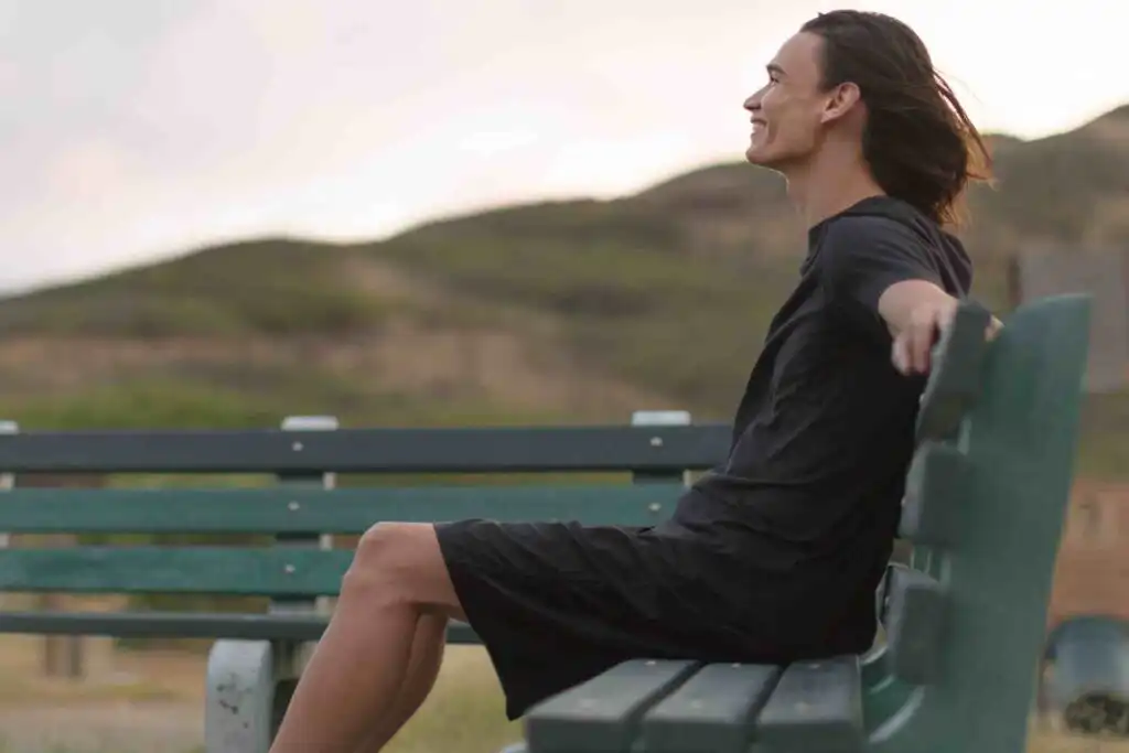 Person sitting on bench outdoors feeling peaceful and calm after recovery