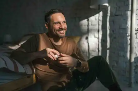 Man holding medication smiling showing progress in addiction recovery treatment