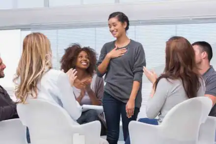 Woman sharing progress in group therapy for prescription drug addiction recovery